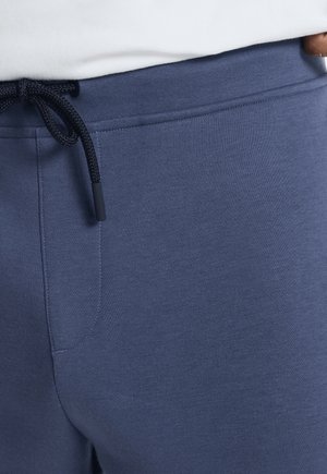 Navy blue sweatpants made of soft fabric, featuring a drawstring waist, smooth texture, and a single side pocket.