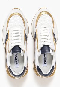 Baskets blanches avec des accents dorés et marine, textures en maille et lisses, semelle matelassée et un design à lacets comportant six oeillets.