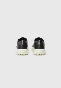 Black sneakers with a smooth leather upper, matte finish, and contrasting white rubber sole; padded collar and reinforced heel detail.