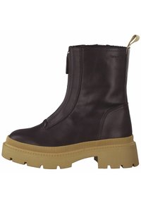 Bottines en cuir marron avec une semelle épaisse et texturée couleur sable. Elles sont dotées d'une fermeture éclair sur le côté et d'une boucle à l'arrière pour un enfilage facile.