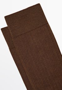 Brune ribbede sokker med en glat tekstur og en bred manchet øverst. Ingen synlige mønstre eller detaljer. Blødt materiale, egnet til daglig brug.