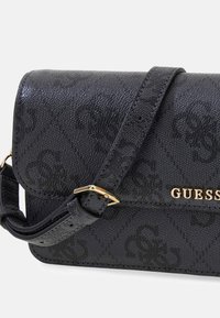 Sac bandoulière synthétique noir avec finition texturée, ferrure dorée et détails de logo embossés. Comprend une sangle ajustable et une fermeture à rabat.