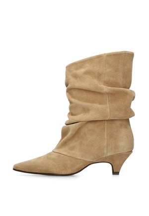 Beige suède midkuit laars met puntige neus en lage kittenhak, zijaanzicht op een witte achtergrond.