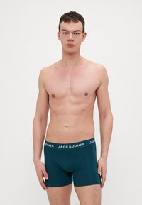 Dunkeltürkisfarbene Boxershorts mit einem schwarzen Bund, auf dem "JACK & JONES" in weißer Schrift steht. Weicher, passgenauer Stoff mit einer glatten Textur.