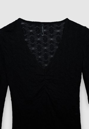 Top nero a maniche lunghe con scollo a V, tessuto strutturato con motivi floreali e dettaglio arricciato al centro del busto.