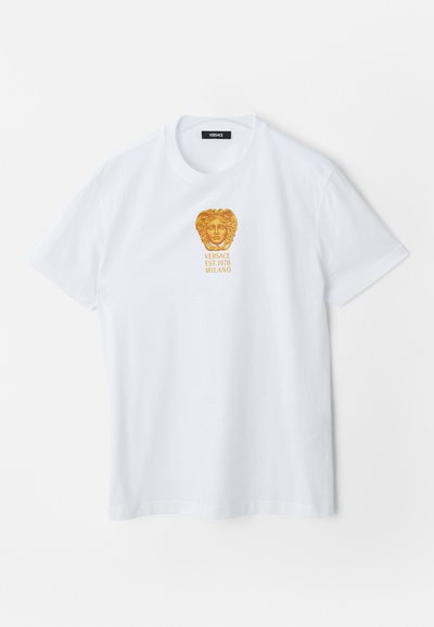 White short-sleeve t-shirt with gold Medusa head logo and "Versace Est. 1978 Milano" text centered on the chest.