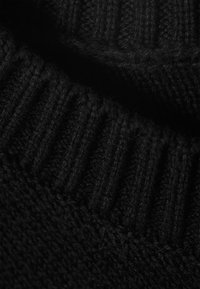 Tissu tricoté noir avec une texture côtelée et des bords lisses, présentant une composition dense et douce ainsi qu'une couleur profonde et uniforme sur toute la surface.