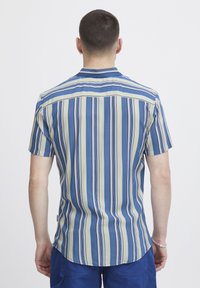 Camicia a maniche corte con strisce verticali blu, beige e rosse; tessuto leggero; colletto a polo; orlo curvo.