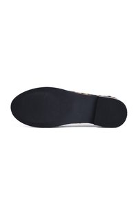 Semelle de chaussure plate noire avec des zones de grip texturées au talon et à l’avant du pied, présentée sur fond blanc.