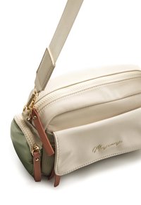 Beige Nylon-Umhängetasche mit grünem Boden, goldfarbenen Reißverschlüssen und hellbraunen Akzenten. Verfügt über einen abnehmbaren Riemen und eine strukturierte Oberfläche.