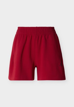 Κόκκινα αθλητικά σορτς με ελαστική μέση και διακριτικό λογότυπο στο κάτω αριστερό πόδι, εμφανιζόμενα σε απλό φόντο.