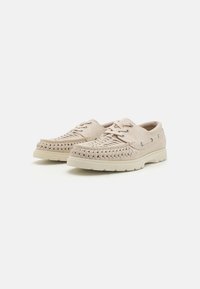 Zapatos de cuero beige con detalles trenzados en la puntera, cordones redondos y una suela de goma ligera. Presenta ojales metálicos para los cordones.