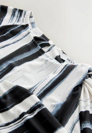 Sort, hvid og blå mønstret top med rund halsudskæring, knappedetalje på ryggen og let, glat stof.