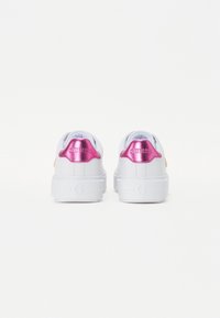 Valkoiset lenkkarit, joissa on paksu pohja, kiiltävät vaaleanpunaiset yksityiskohdat kantapäässä ja logossa, pehmeä nahkamateriaali ja pehmustettu vuoraus.