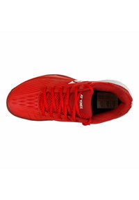 Scarpa da atletica rossa con tomaia in mesh testurizzato, sistema di allacciatura prominente e marchio bianco. Presenta un profilo snello e una punta rinforzata.
