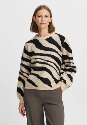 Pletený svetr s béžovým základem a výraznými černými pruhy jako zebra, s kulatým výstřihem a volnými dlouhými rukávy. Měkká textura.
