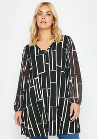 Tunic in bianco e nero con motivo a righe, caratterizzata da un collo a V, maniche lunghe trasparenti e una silhouette sciolta e fluida. Linee geometriche testurizzate su tutta la superficie.