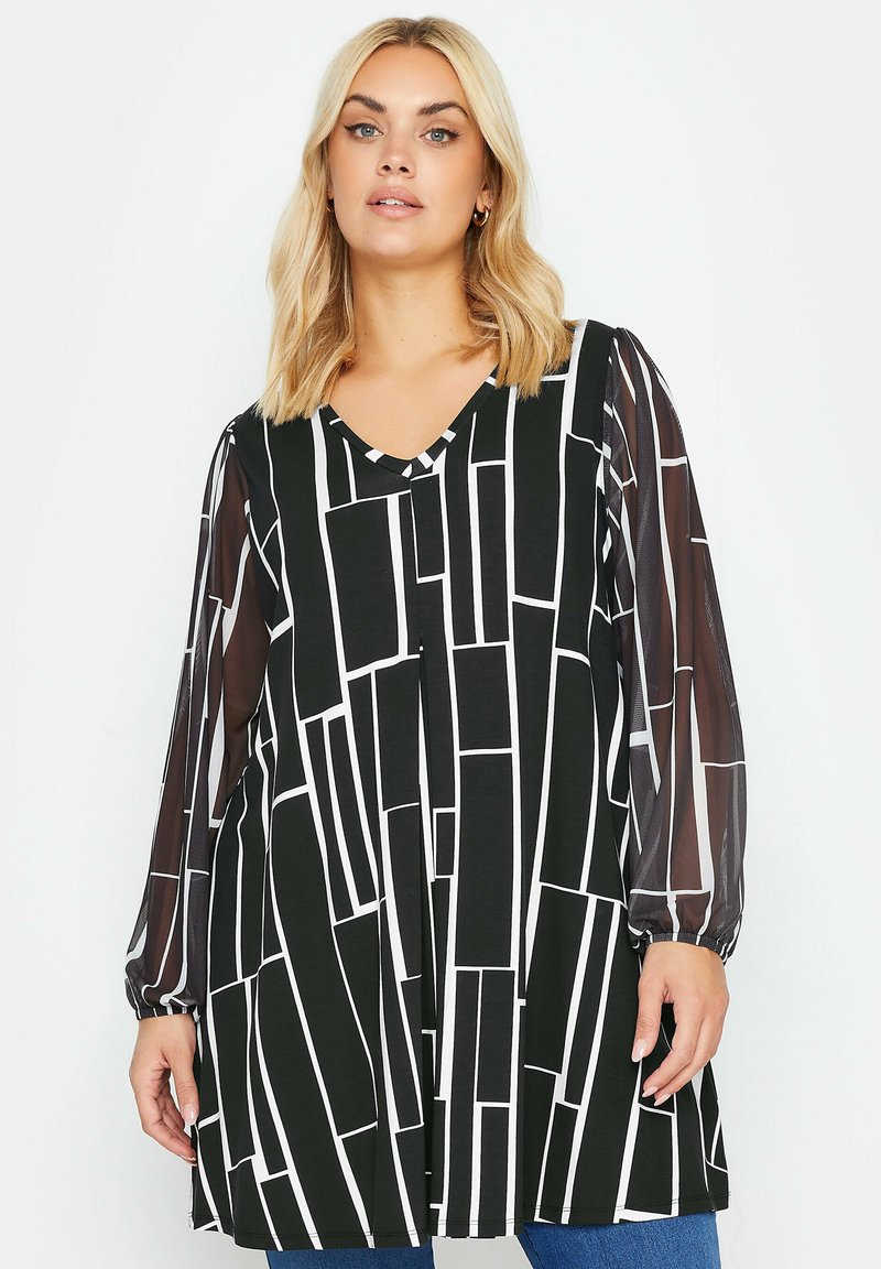 Tunic in bianco e nero con motivo a righe, caratterizzata da un collo a V, maniche lunghe trasparenti e una silhouette sciolta e fluida. Linee geometriche testurizzate su tutta la superficie.