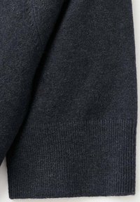 Donker marineblauw gebreid tricot met een gladde textuur, voorzien van een geribbelde zoom aan de onderkant. Subtiele spikkels kunnen zichtbaar zijn.