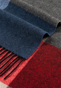 Wool scarf in navy, gray, and red plaid pattern. Features soft texture, finished edges, and long fringes on the red section.