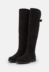 Knee-high black suede boots with a smooth texture, side zipper, and flat sole. Reinforced stitching on the upper. No visible logos or patterns.