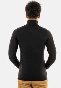 Pullover nero a maniche lunghe con colletto alto, design aderente e texture a maglia liscia. Stile minimalista, senza motivi o dettagli visibili.