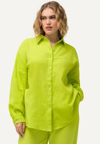 Camicia verde lime, con bottoni, realizzata in un tessuto texture e dal taglio morbido, con maniche lunghe e colletto classico, dotata di bottoni in argento.