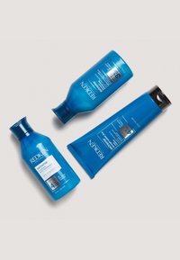 Tre REDKEN hårvårdsprodukter i klarblå förpackning: två flaskor och en tub, märkta "extreme" och med varierande storlekar och former.