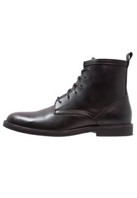 Stivaletto in pelle nera con finitura liscia, punta tonda, lacci frontali e linguetta sul retro; presenta dettagli in cucitura.