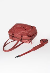 Red leather handbag with a zip closure, dual handles, and detachable strap. Features smooth texture and subtle stitching details.