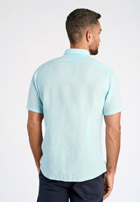 Kort shirt met korte mouwen in lichtblauw, gemaakt van een licht doorschijnende, gestructureerde stof, met een puntige kraag en een afgeronde zoom. Zichtbare stiksel details.