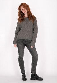 Szürke kötött pulóver gyémántmintával, sötétszürke skinny farmerral és fekete vastag szárú bokacsizmával párosítva. Simább textúra, laza fazon.