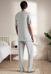 Lys grå loungewear sæt lavet af blødt stof, bestående af en kortærmet top med rund hals og lange bukser med en afslappet pasform.