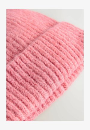 Tejido de punto rosa suave y texturizado con acanalados elevados, doblado de manera ordenada, mostrando una apariencia esponjosa y peluda con una coloración uniforme.