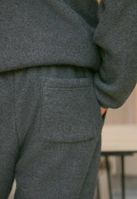 Szürke bolyhos loungewear, laza szabású. Hátsó zsebe egyenes varrással készült, puha tapintású és kényelmes megjelenésű.