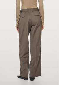Brown pinstriped trousers with a wide-leg design, featuring a belted waist and two back pockets. Smooth texture and tailored fit.