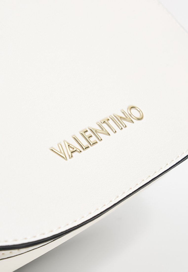 Surface en cuir blanc avec le logo Valentino doré et des coutures visibles le long du bord.