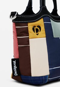 Sac cabas matelassé en panneaux multicolores de cuir et tissu. Comprend un logo, des accessoires en argent et des coutures contrastantes. Forme rectangulaire.