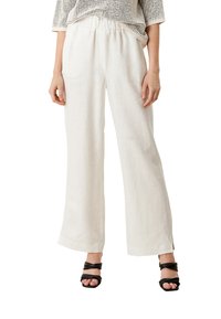 Breda byxor i krämfärgat tyg, tillverkade i lätt material, med elastisk midja och sidoplysch, kombinerade med svarta sandaletter med remmar.