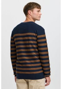 Pull marinière bleu marine avec des rayures horizontales orange et marron, des poignets côtelés et un col rond. Texture douce et coupe standard.