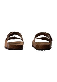 Bruine suede sandalen met twee verstelbare banden, een kurken voetbed en een gestructureerde rubberen zool, gezien vanaf de achterkant.