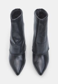 Stivaletti neri in pelle con punta affilata, silhouette aderente e superficie liscia. Presentano cuciture sottili e nessun elemento hardware visibile.
