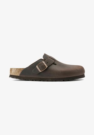 Brown leather clog with a cork footbed, adjustable buckle, smooth exterior, rounded shape, and textured rubber outsole.