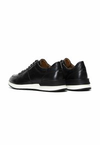 Zapatillas de cuero negro con punta redonda, acabado texturizado, diseño con cordones y suela blanca en contraste, con detalles de costura sutiles.