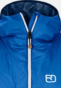 Blaue isolierte Jacke mit Kapuze, ausgestattet mit einem weißen Reißverschluss und einem kleinen Logo auf der Brust. Der Stoff ist glatt und glänzend, mit Rautenmuster.