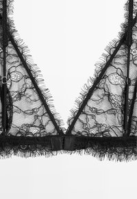 Black lace bralette featuring a triangular shape, scalloped edges, floral pattern, and adjustable straps. Soft, sheer texture enhances design.