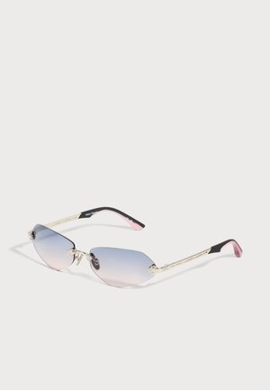 Lunettes de soleil sans monture avec verres à dégradé bleu-rose, branches dorées et embouts incurvés noir-rose sur fond neutre.