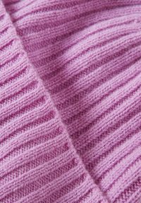 Tessuto lavorato a maglia in morbido rosa, caratterizzato da una texture a costine con strisce verticali alternate e una leggera peluria, che evocano calore e comfort.