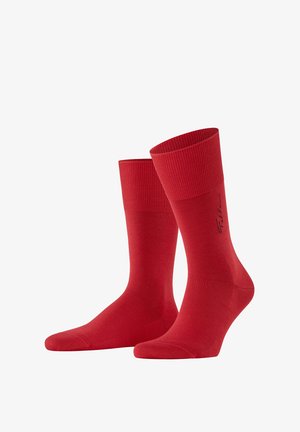 Une paire de chaussettes rouges unies avec un poignet texturé et un petit logo noir sur le côté.