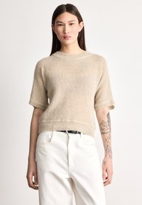 Trumpomis rankovėmis megztinis smėlio spalvos, su ribbiniu apačios ir rankogalių raštu, derinamas su baltais džinsais. Minkšta tekstūra, laisvo stiliaus prigludimas.